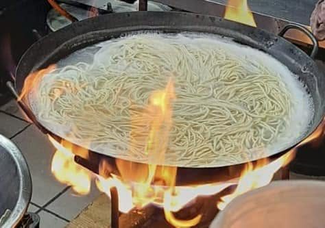 Noodles cooking in a wok over open flame at Hua Lien Chinese Take-Aways